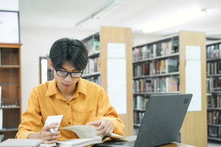 Young collage student using computer and mobile device studying online.の写真素材