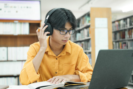 Young collage student using computer and mobile device studying online.の写真素材