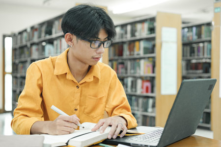 Young college student using computer and mobile device studying online.
