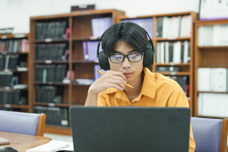Young collage student using computer and mobile device studying online.の写真素材