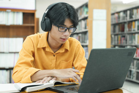 Young collage student using computer and mobile device studying online.の写真素材