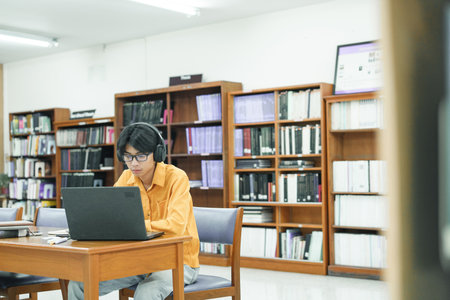 Young college student using computer and mobile device studying online.の写真素材