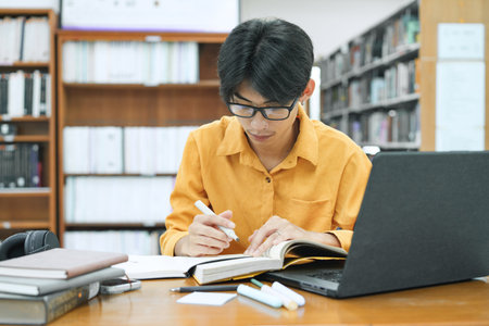 Young collage student using computer and mobile device studying online.