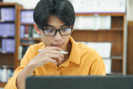 Young collage student using computer and mobile device studying online.の写真素材
