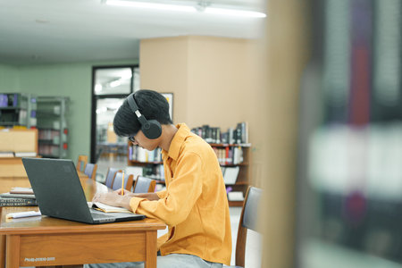 Young college student using computer and mobile device studying online.の写真素材