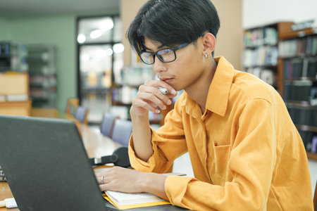 Young collage student using computer and mobile device studying online.の写真素材