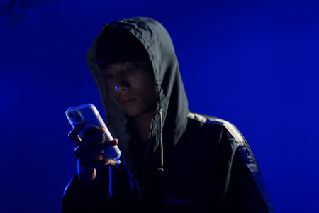 Hacker using smartphone for phishing attack and data theft in dark cyber environment