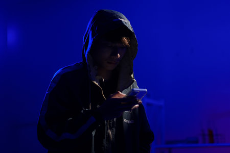 Hacker using smartphone for phishing attack and data theft in dark cyber environment