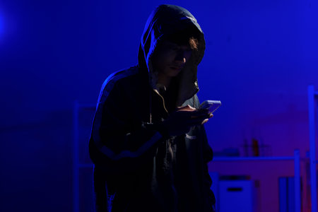 Hacker using smartphone for phishing attack and data theft in dark cyber environment