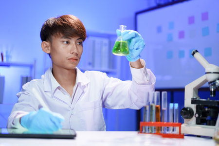 A young male scientist examining a in beaker a lab.の写真素材
