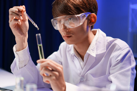 Scientists working in Laboratory using pipette dropping liquid sample into test tube.