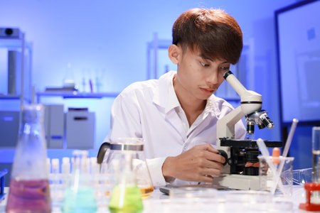 Young scientist looking through a microscope in the laboratory.