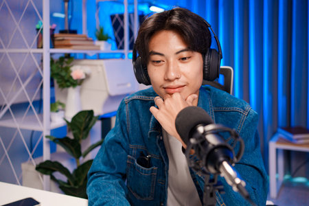 Young man podcasting with thoughtful expressionの写真素材