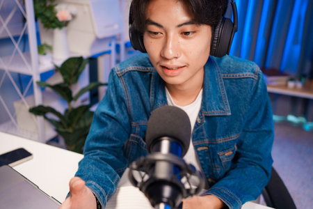 Smiling man podcaster make audio podcast with headphones and microphone in modern home studio.の写真素材