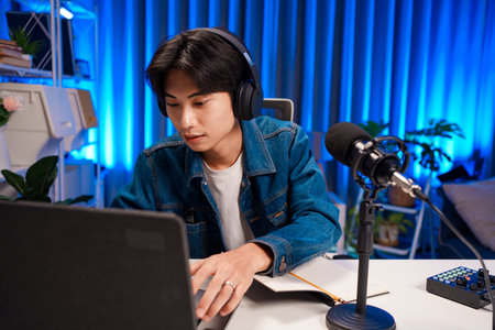 Smiling man podcaster make audio podcast with headphones and microphone in modern home studio.の写真素材