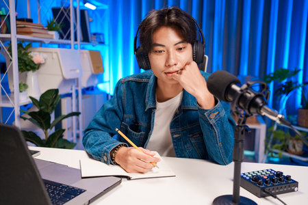 Man writing podcast notes in creative setupの写真素材