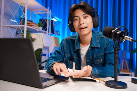 Smiling man podcaster make audio podcast with headphones and microphone in modern home studio.