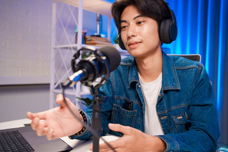 Smiling man podcaster make audio podcast with headphones and microphone in modern home studio.