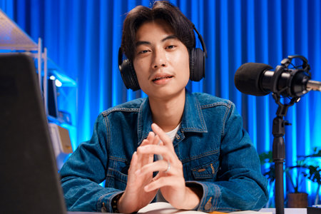 Smiling man podcaster make audio podcast with headphones and microphone in modern home studio.の写真素材