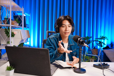 Smiling man podcaster make audio podcast with headphones and microphone in modern home studio.