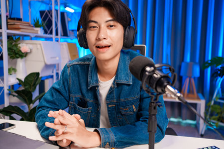 Smiling man podcaster make audio podcast with headphones and microphone in modern home studio.の写真素材