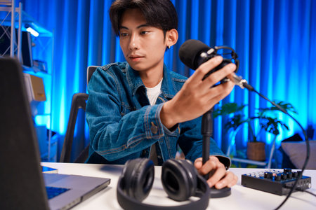 Young man adjusting microphone for podcast recording in home studioの写真素材