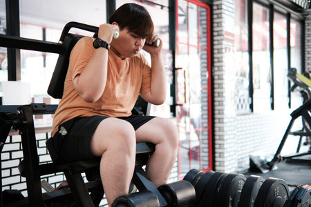 A plus-size man doing an abdominal crunch exercise on a machine at the gym.の写真素材