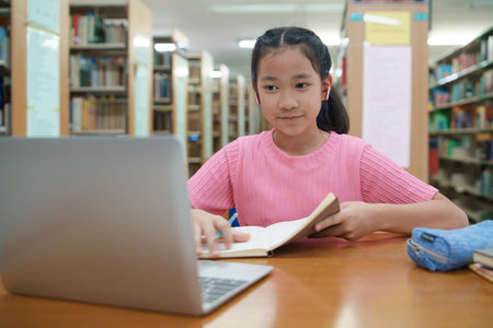 School student girl using a laptop in a library at school.