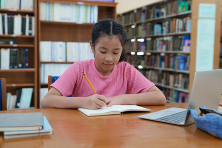 Student learning online class by using laptop computer and writing notebook at workplace, E learning...