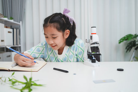 Elementary School Girl Taking Notes Science Experiment Microscope STEM Researchの写真素材