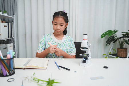 Young student preparing for science study beside microscope showing STEM curiosity and learning focusの写真素材