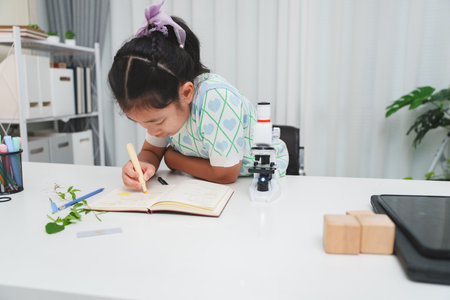 Elementary School Girl Taking Notes Science Experiment Microscope STEM Researchの写真素材
