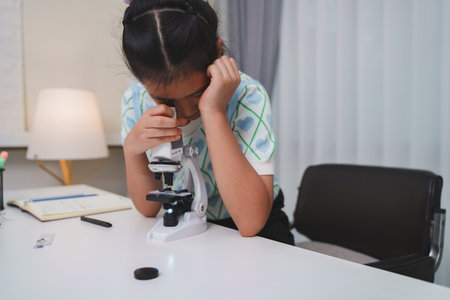 Elementary student practicing science skills using microscope during hands on learning activityの写真素材
