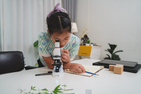 Elementary student practicing science skills using microscope during hands on learning activityの写真素材
