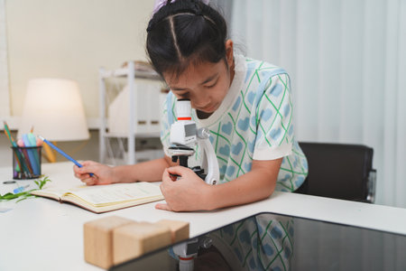 Young student exploring microscope highlighting STEM curiosity and scientific learning skillsの写真素材