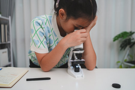 Elementary student practicing science skills using microscope during hands on learning activityの写真素材