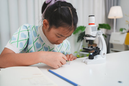 Young student preparing slide for microscope study demonstrating STEM curiosity and scientific skillsの写真素材