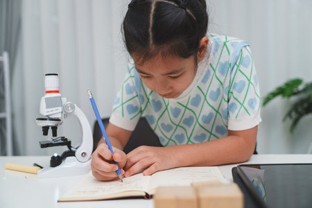Elementary School Girl Taking Notes Science Experiment Microscope STEM Researchの写真素材