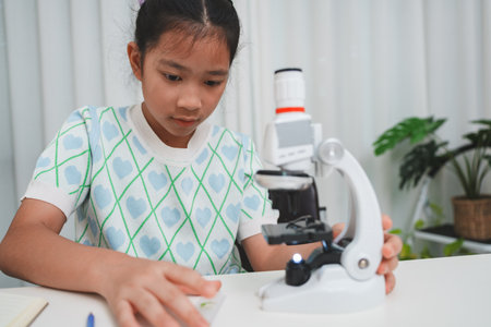 Young student preparing slide for microscope study demonstrating STEM curiosity and scientific skillsの写真素材