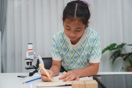 Elementary School Girl Taking Notes Science Experiment Microscope STEM Researchの写真素材