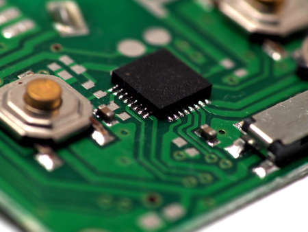 Green Printed Circuit Board (PCB) with some Surface Mount Device (SMD) components and chips. Shoot...