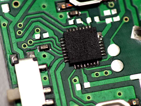 Green Printed Circuit Board (PCB) with some Surface Mount Device (SMD) components and chips. Shoot...