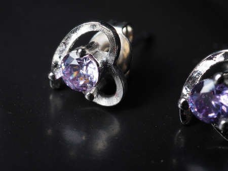 Close up shoot of silver earring with faceted amethyst gem. Shot on black background.の写真素材
