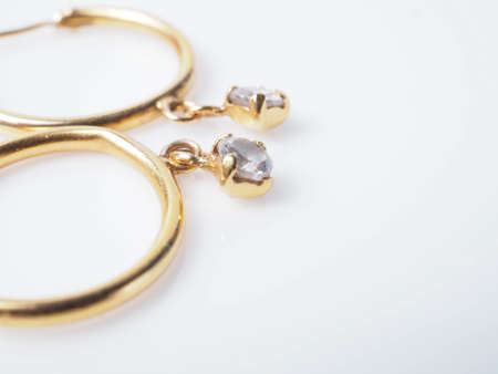 Close up shoot of a pair of golden earrings with diamonds. Shoot on a white isolated backgroundの写真素材