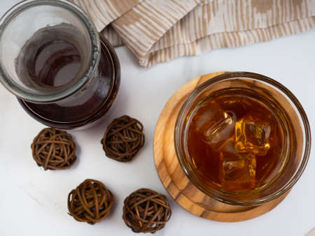 A cup of iced coffee on a wooden table with a jar container. Shoot on dark mood style