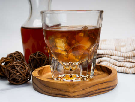 A cup of iced coffee on a wooden table with a jar container. Shoot on dark mood styleの写真素材