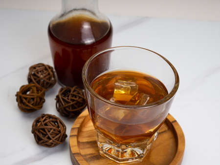 A cup of iced coffee on a wooden table with a jar container. Shoot on dark mood styleの写真素材