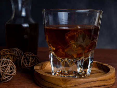 A cup of iced coffee on a wooden table with a jar container. Shoot on dark mood styleの写真素材