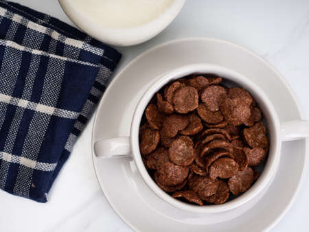 Chocolate cereal with milk on a white bowl, placed on a white marble tableの写真素材