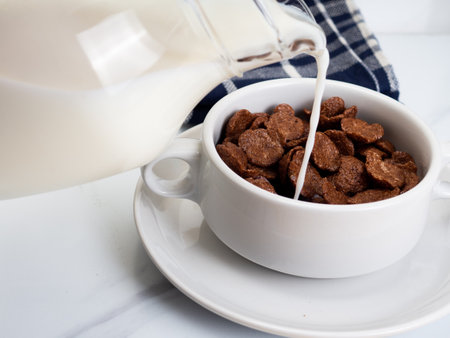 Chocolate cereal with milk on a white bowl, placed on a white marble tableの写真素材